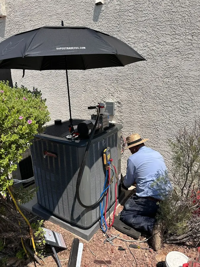 HVAC technician performing outdoor AC maintenance in Harrisonville