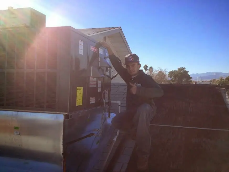 HVAC technician performing Boiler Repair on a rooftop unit in Harrisonville